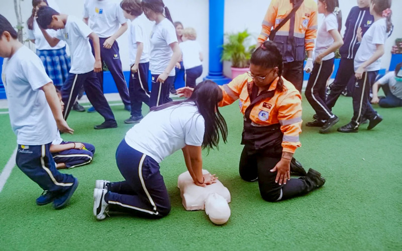 Estudiantes de Emergencias Médicas instruyen a estudiantes de colegio en primeros auxilios. 