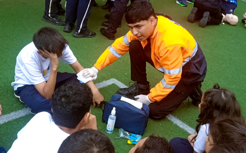 Estudiantes de Emergencias Médicas instruyen a estudiantes de colegio en primeros auxilios. 