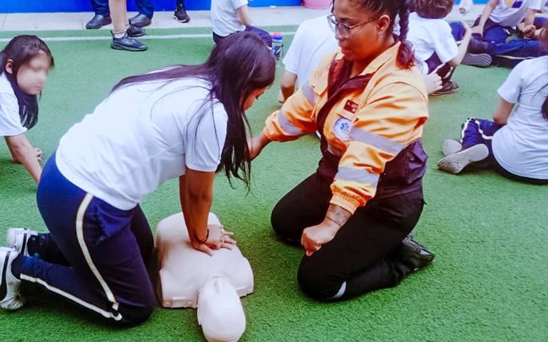 Estudiantes de Emergencias Médicas instruyen a estudiantes de colegio en primeros auxilios. 